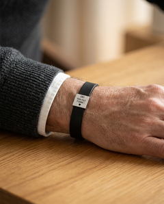 Bracelet noir porté au poignet, sur une table en bois