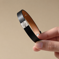 Bracelet noir avec plaque argentée « Ta fille t'aime » tenu en main